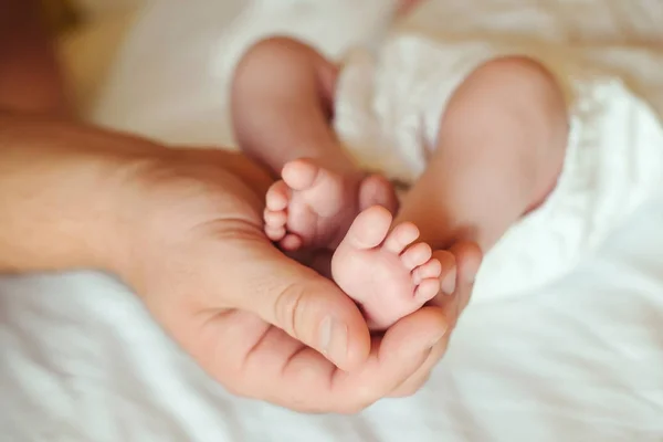 Pieds de bébé dans les mains du père . — Photo