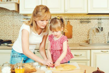 Genç anne ve sevimli küçük kızı çerezleri ve mutfakta eğlenerek fırında.