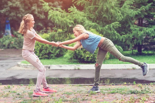 Irmãs gêmeas se divertir juntos em um parque em um verão . — Fotografia de Stock