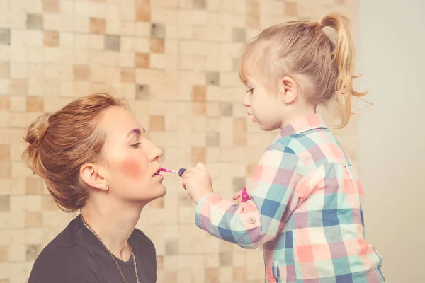 Roztomilá holčička dělá make-up pro její krásnou matku. Tónovaný. — Stock fotografie