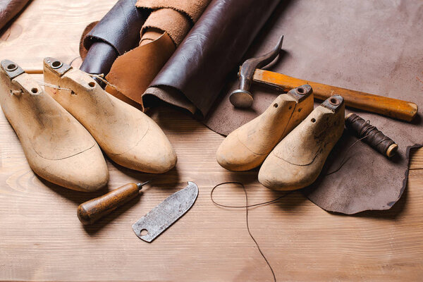 Leather in rolls, cobbler tools and shoe lasts in workshop. Leather craft tools.