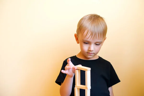 Actieve grappige jongen jongen is het opbouwen van een structuur uit de natuur houten bouwstenen. — Stockfoto