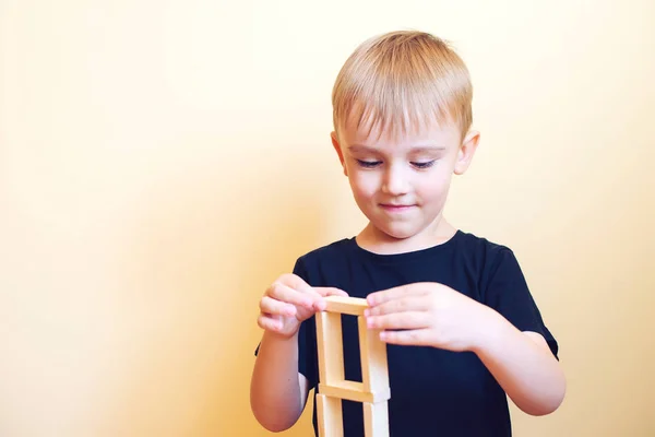 Actieve grappige jongen jongen is het opbouwen van een structuur uit de natuur houten bouwstenen. — Stockfoto
