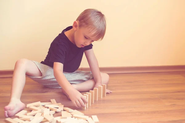 Leuke jongen spelen op een vloer met houten blokken. Ontwikkeling van speelgoed. — Stockfoto