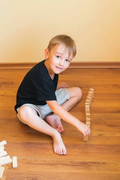 Leuke jongen spelen op een vloer met houten blokken. Ontwikkeling van speelgoed. — Stockfoto