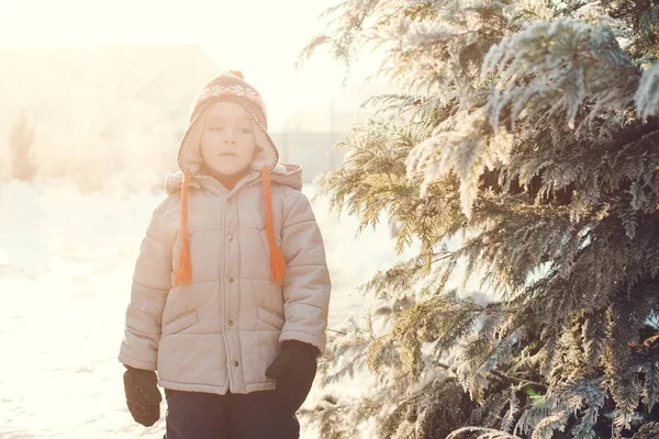 Aranyos fiú, pom pom meleg kalapot visel, a hideg téli napon játszani a kültéri, hó portréja. — Stock Fotó
