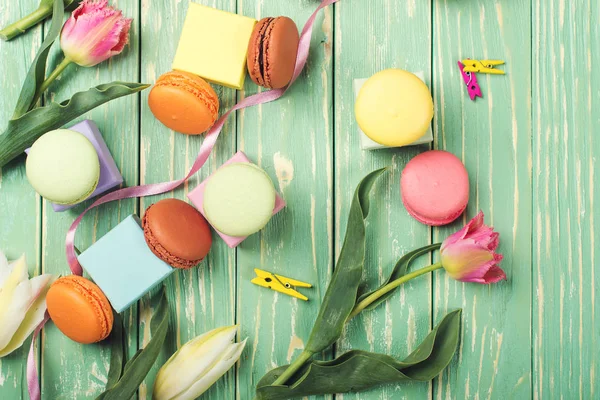 Belles tulipes avec des macarons colorés sur fond de bois verdoyant. Espace de copie. Pose plate . — Photo