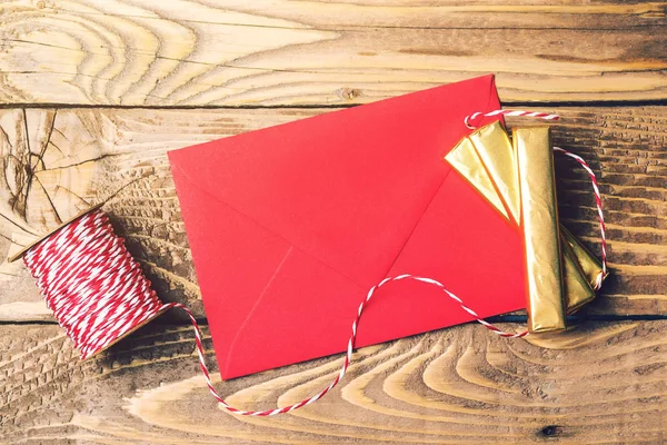 Red envelope with golden gifts on wooden background. Top view, copy space.