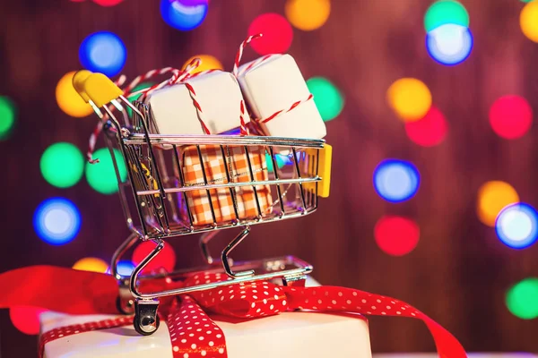 Kerstcadeau selectievakjes in een winkelwagentje op achtergrondkleur bokeh. Kerstmis verkoop concept. — Stockfoto