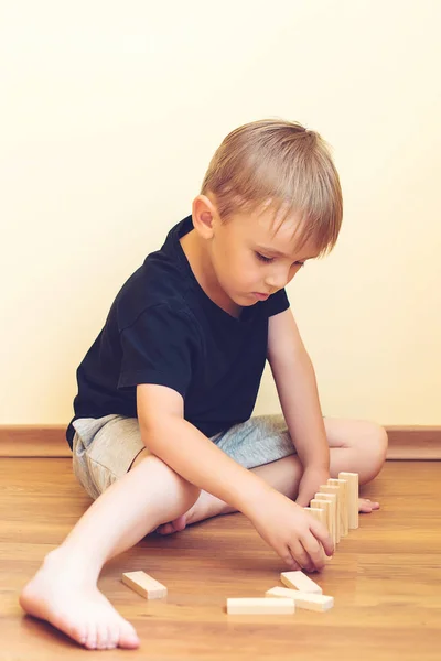 Leuke jongen spelen op een vloer met houten blokken. Ontwikkeling van speelgoed. — Stockfoto