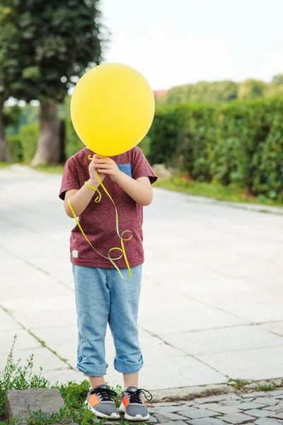 Mały chłopiec śmieszne gry z zewnątrz żółty balon. — Zdjęcie stockowe