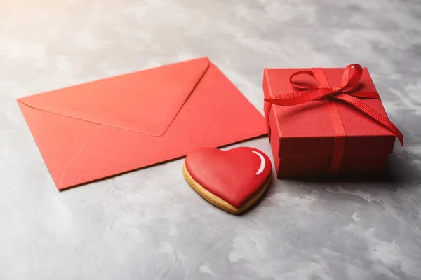Cartão dos Namorados com envelope vermelho, caixa de presente e pão de gengibre no fundo texturizado cinza . — Fotografia de Stock