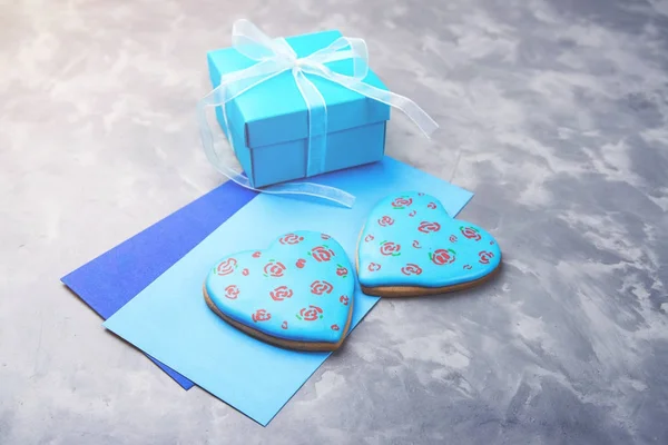 Caja regalo azul, dos sobres y dos corazones de pan de jengibre sobre fondo de hormigón . — Foto de Stock