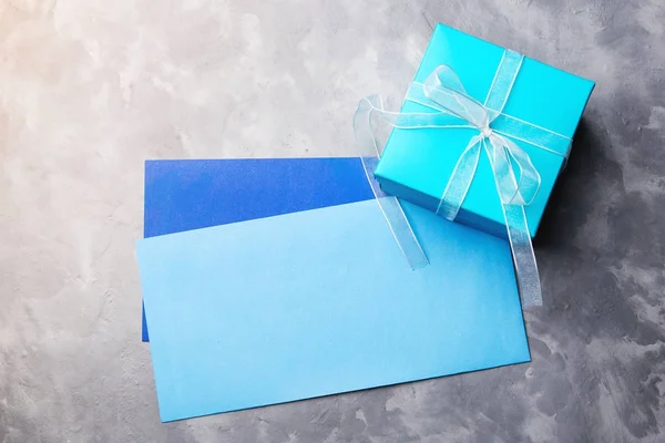 Coffret cadeau bleu et deux enveloppes sur fond béton . — Photo