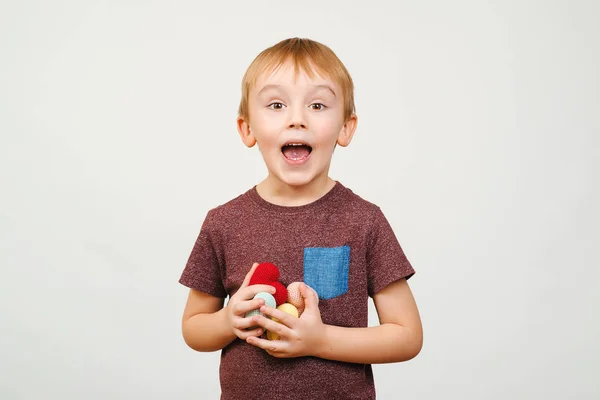 Gelukkig schattige jongen houdt een heleboel gekleurde gebreide harten, geïsoleerd op witte achtergrond. — Stockfoto