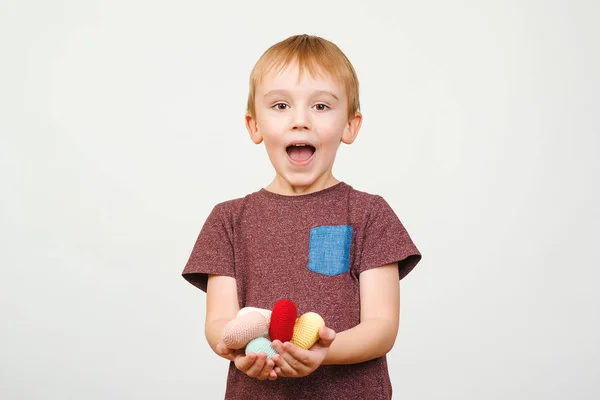 Šťastný roztomilý chlapec drží hodně barevné pletené srdce, izolované na bílém pozadí. — Stock fotografie