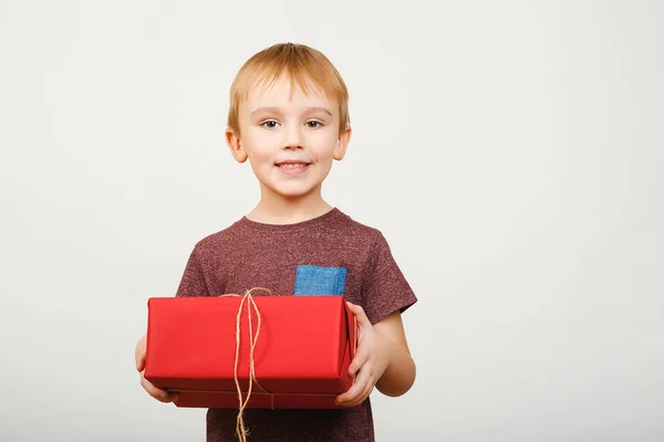 Mutlu sevimli küçük çocuk beyaz arka plan üzerinde izole kırmızı hediye kutusu holding. — Stok fotoğraf