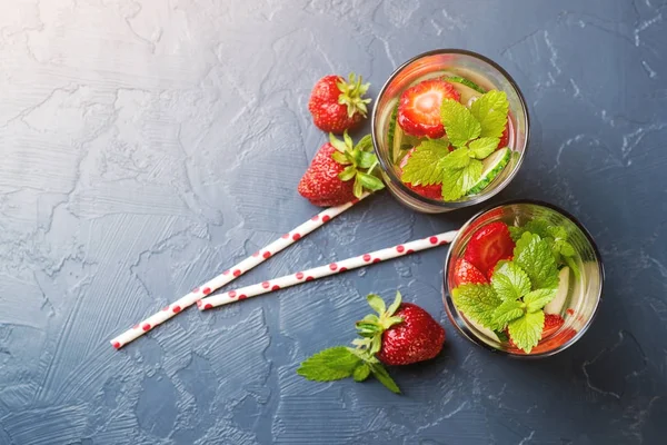 Kalla och uppfriskande infunderas detox vatten med jordgubbar och gurka i glas på svart bakgrund. Ovanifrån. — Stockfoto
