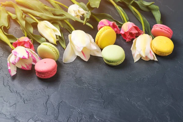 Colorful tulips and macaroons on black background. Space for text. — Stock Photo, Image