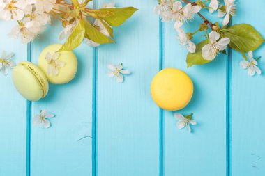 Bahar çiçekleri ve mavi arka plan üzerinde renkli macaroons.