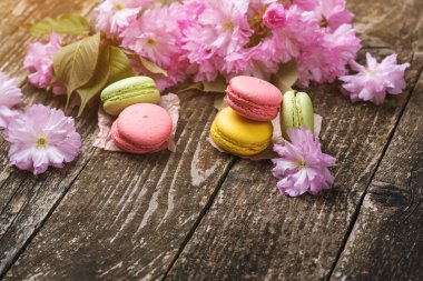 Delisious macarons koyu ahşap zemin, kopya alanı, seçici odak üzerine çiçeklerle pembe sakura.