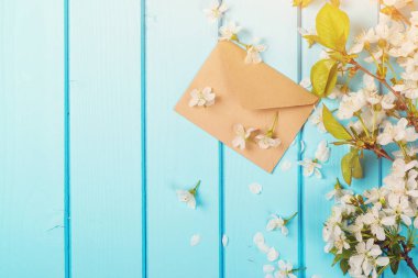 Zarf üzerinde gökyüzü mavi ahşap arka plan bahar çiçekleri ile. Uzay kopyalayın. Düz yatıyordu.