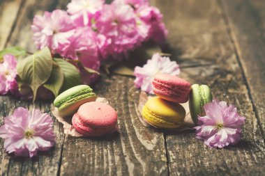 Delisious macarons koyu ahşap arka plan üzerinde kopya alanı, seçici odak pembe sakura çiçeklerle.