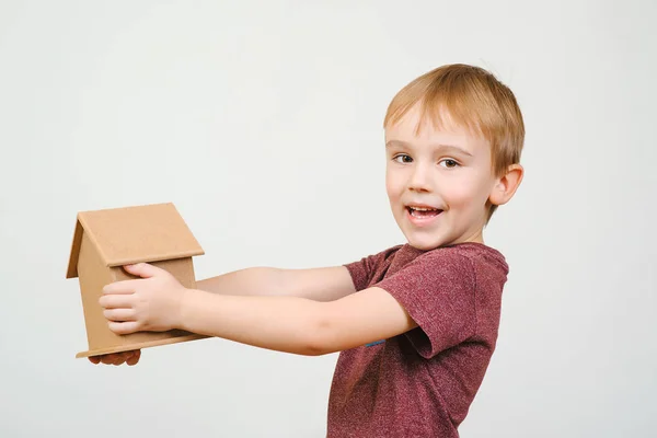 Niedlichen kleinen Jungen halten eine kleine Hausbank. Konzepte, die Geld für Haus und Zukunft sparen. — Stockfoto