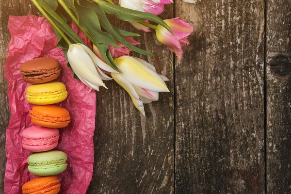 Macarons colorés et belles tulipes sur fond bois rustique foncé avec espace de copie. Présent le jour de la fête des mères, de la Saint-Valentin ou de la fête des femmes . — Photo