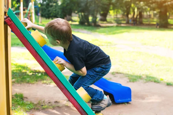 Netter kleiner Junge hat Spaß und klettert auf Spielplatz. — Stockfoto