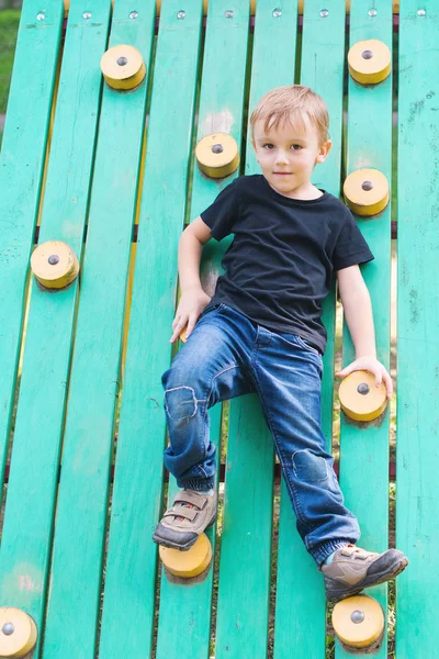 Petit garçon mignon s'amusant et grimpant sur une aire de jeux extérieure . — Photo