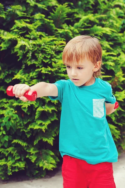 Kleine jongen hebben trainen met halters buiten. — Stockfoto