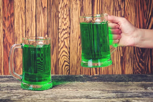 Duas canecas de cerveja verde no fundo de madeira rústica . — Fotografia de Stock