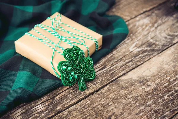 Stilvolle Geschenkschachtel mit grünem Seil und Kleeblatt, auf rustikalem Holzgrund. — Stockfoto