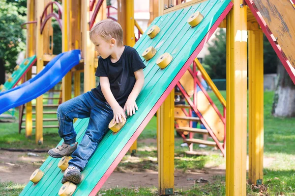 Netter kleiner Junge hat Spaß und klettert auf Spielplatz. — Stockfoto