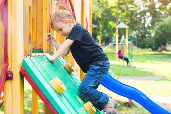 Netter kleiner Junge hat Spaß und klettert auf Spielplatz. — Stockfoto