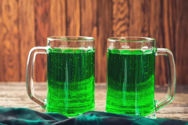 Duas canecas de cerveja verde no fundo de madeira rústica . — Fotografia de Stock