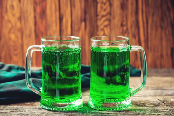 Duas canecas de cerveja verde no fundo de madeira rústica . — Fotografia de Stock