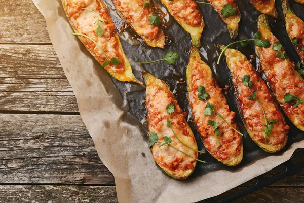 Calabacín relleno al horno con carne en una sartén sobre tablas de madera . — Foto de Stock