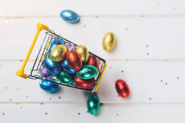 Panier avec oeufs de Pâques colorés sur fond de bois blanc . — Photo