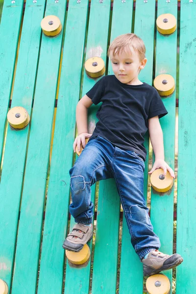 可爱的小男孩有乐趣和攀登在户外操场上. — 图库照片