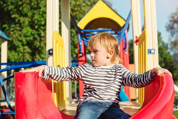 Glücklicher kleiner Junge auf dem Spielplatz bei sonnigem Tag. — Stockfoto