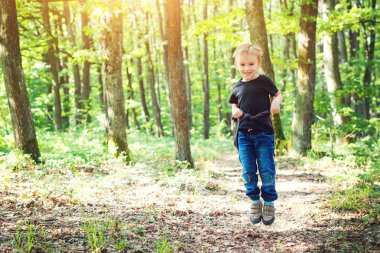 Güneşli bir günde doğa üzerinde atlama mutlu sarışın çocuk.