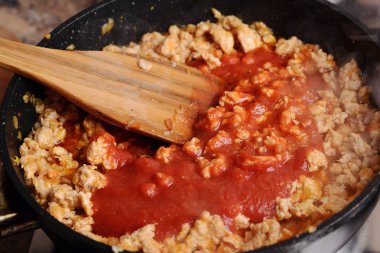 Bir tavada domates soslu kızarmış tavuk forcemeat.