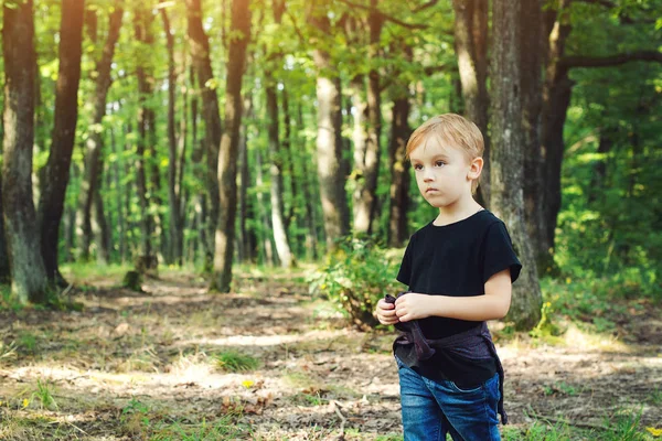 Menino olhando para longe na floresta durante a jornada familiar . — Fotografia de Stock