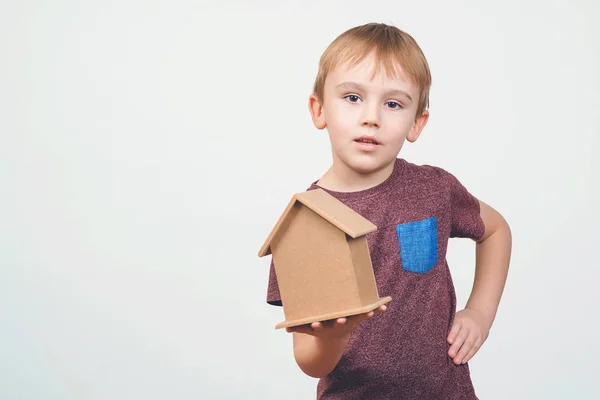 Niedlichen kleinen Jungen halten eine kleine Hausbank. Konzepte, die Geld für Haus und Zukunft sparen. — Stockfoto
