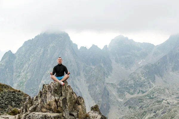 Young man meditating yoga at top of mountain. Concept travel and harmony with nature. — Stock Photo, Image