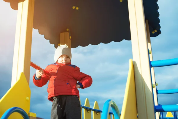 Garçon mignon s'amuser sur une aire de jeux extérieure par temps froid . — Photo