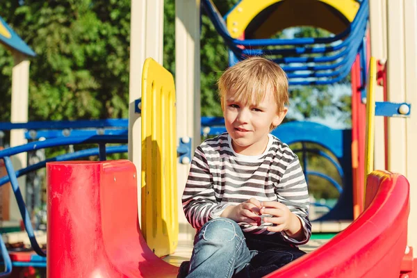 Glücklicher kleiner Junge auf dem Spielplatz bei sonnigem Tag. — Stockfoto