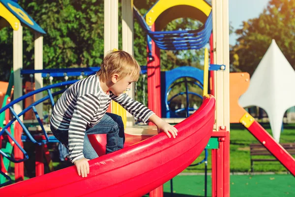 Glücklicher kleiner Junge auf dem Spielplatz bei sonnigem Tag. — Stockfoto
